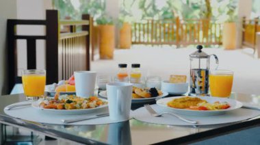 Hotel breakfast at luxury restaurant with tropical atmosphere. Fresh food and juices on buffet table. Enjoy outdoor served breakfast surrounded by palm trees on your vacation.