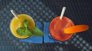 Restoran masasında kağıt pipetli papaya ve mango smoothie manzarası, ferahlatıcı ve sağlıklı bir içecek. Smoothie 'ye yakın çekim, detoksdan arındırma ve temiz yemek. Canlı renkler. Doğal içecek..