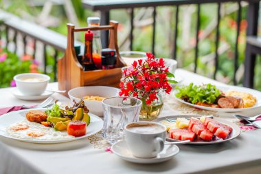 Bright morning food in summer garden terrace. Breakfast on backyard. Homemade healthy food with avocado, eggs and fresh fruit with green summer valley on background.