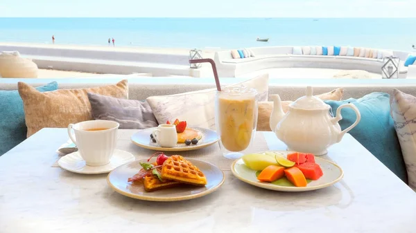 Beachfront hotel breakfast, beautiful morning on beach. Enjoy delicious meal with sea view. Relax and enjoy ocean and sound of waves. Beach, vacation, tropical holidays, travel.