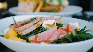 Close up of Fresh tuna sashimi salad with fruits, cheese, and arugula. Perfect for low-carb diets. Served at restaurant table.