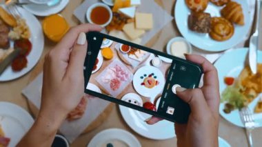 Woman influencer and a blogger, records her restaurant breakfast experience on her phone camera. Close-up shots of the sweet food are shared on her social media.