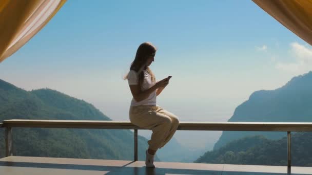 Woman Holding Smartphone Scrolling Screen Sitting Wooden Terrace Looking Out — Stock Video