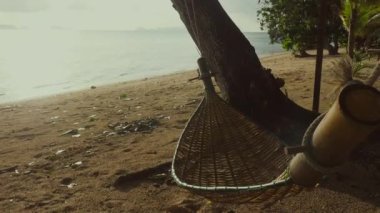 Tropikal bir ada sahilinde saman hamağı, turkuaz su ve gün doğumunda el değmemiş sahil şeridi. Tropik cennet. Mükemmel bir seyahat ve turizm merkezi..