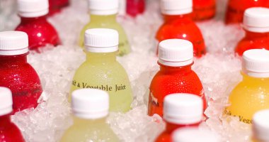 Süpermarkette renkli taze sıkılmış meyve ve sebze suyuyla dolu plastik şişeler. Yakın çekim..