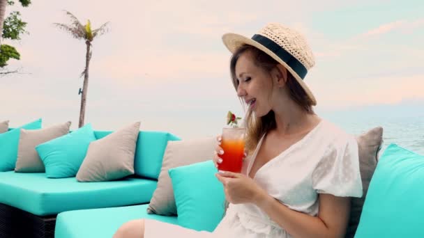 모자를 해변의 소파에서 칵테일을 마시며 아름다운 경치를 휴일에 — 비디오