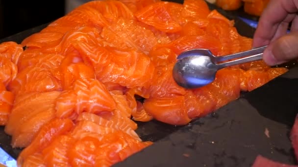 豪华餐厅的新鲜海鲜自助餐以美味的切碎鲑鱼为特色 精心准备 可随时享用 人的手拿一块金属钳做的好吃的片 — 图库视频影像