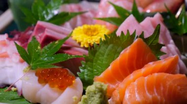 Dilimlenmiş taze balık sashimi ve havyar. Japon lokantasındaki çiğ deniz ürünlerinin lezzeti. Lezzetli sashimi karışımı hirame, maguro, tako. Japon mutfağı güzel bir restoranda servis edilir..