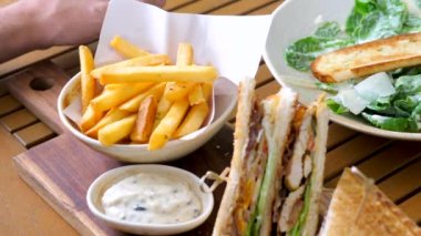 Erkek elinin yakınından fast food, salata ve mayonez soslu patates kızartması al. Sağlıksız yiyecekler. Yavaş çekim.