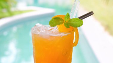 Lüks tatil köyü kaplıcasında yüzme havuzunun yanında serinletici portakal suyu, buz ve nane yaprağı. Tatilde içmek için sağlıklı bir yaz içeceği..