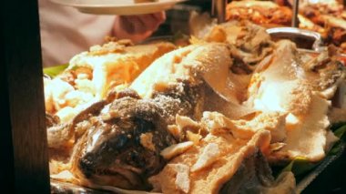 Şef müşteriler için tabağa pişmiş somon balığı koyar. Elit bir açık büfede servis. Lüks restoranda et ve deniz ürünleri ile yemek büfesi..