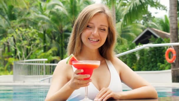白い水着を着た美しい女性がリラックスし 屋外プールでカクテルを楽しみ 彼女の周りの自然 笑顔と楽しみを持っています 熱帯の休日 — ストック動画