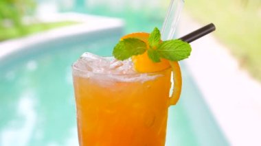 Lüks tatil köyü kaplıcasında yüzme havuzunun yanında serinletici portakal suyu, buz ve nane yaprağı. Tatilde içmek için sağlıklı bir yaz içeceği..