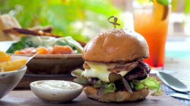 Kırsal bir lokantada sunulan gevrek pastırmalı ve taze sebzeli ağız sulandıran bir çizburger. Sulu köfte mükemmel ızgara yapılır ve susamlı çörekte servis edilir..