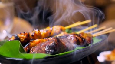 Tavuk dumanla yanıyor. Bambu çubuğunda ızgara tavuk şiş, kömürde kızartılmış. Fıstık soslu, limonlu ve biberli, geleneksel Asya yemeği..