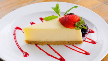 Ev yapımı cheesecake diliminin ahududu soslu ve naneli yakın plan görüntüsü. Restoran ya da fırın için lezzetli ve iştah açıcı bir tatlı..
