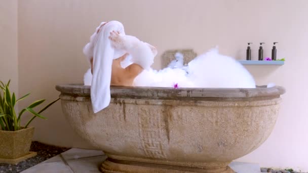 호텔의 목욕이요 아름다운 여자가 이색적 유기적 제품들이 거품으로 가득찬 욕조에서 — 비디오