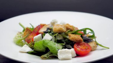 Lezzetli vejetaryen Sezar salatası, sütsüz peynir, taze marul ve olgun vişneli domates. Bir kasede roka ile servis edilmiş, sağlıklı ve lezzetli bir yemek..