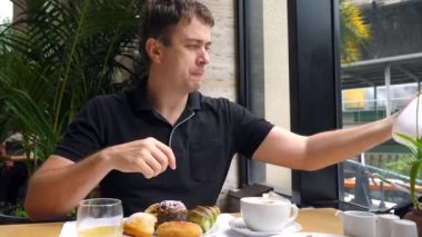 Adam kahvaltısını ya da akşam yemeğini restoranda bitirdi, yüzünü beyaz havluyla temizledi. Mutlu gülen adam yemekten sonra peçeteyle ağzını siliyor. Sağlıksız tatlı yiyecekler ve kafede taze hamur işleriyle..