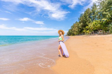Mayo giyen gezgin kadın tropik plaj tatilinin tadını çıkarıyor. Okyanus kıyısında yürüyen mutlu genç bir kızın yaz yaşam tarzı. Temiz suyu olan tropik bir ada plajı. Asya, Tayland 'da tatil