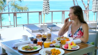 Genç bir kadın yaz mevsiminde tropikal tatil köyünde ya da oteldeki lüks restoranlarda kahvaltı ya da brunch yapar. Kadın turist konsepti. Seyahat, tatil ya da Tayland, Phuket.