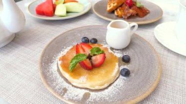 Cozy cafe serving a delicious breakfast. Enjoy a sweet pastry, a cup of tea, and fresh fruits. Relaxed atmosphere of a cafe, perfect for any project related to food, leisure and morning routine.
