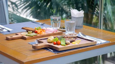 Biftek, ızgara somon, sebze ve ahşap tahtalarda servis edilen aperatiflerle öğle yemeğini yakın..