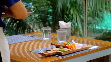 Lüks bir tropikal restoranda garson taze ve lezzetli yemekler servis ediyor. Tropik bir açık hava restoranında güzel yemek servisi. Otel tatili