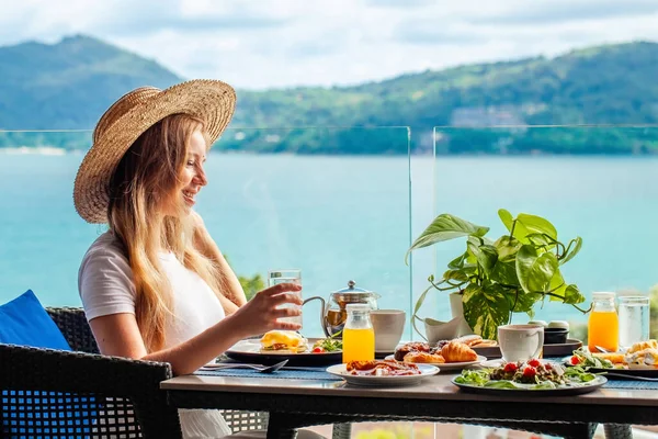Kahve Masasında Oturmuş Deniz Manzaralı Gülümseyen Kadın Bir Bardak Portakal — Stok fotoğraf