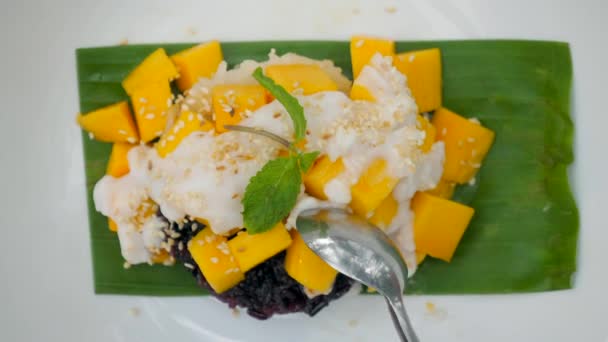 女人用勺子把芒果粘在一起 泰国菜 顶级的甜而粘的甜点与新鲜的芒果 和丰盛的椰奶 靠近点 — 图库视频影像
