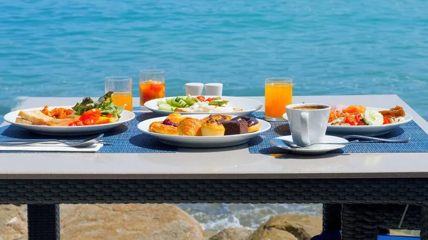Delicious breakfast on coast, surrounded by the stunning views of the beach. Variety of fresh food on set table at luxury seaside restaurant.