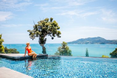 Kadınlar lüks bir otel tesisinde havuz başında rahatlatıcı bir yaz tatilinin tadını çıkarıyorlar. Kız güneşin tadını çıkarıyor, nefes kesici okyanus manzarasını seyrediyor..