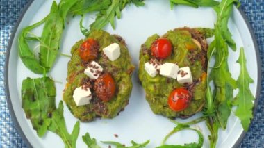 Avokado tostlu, Yunan peynirli ve çavdar ekmekli vişneli domatesli sağlıklı kahvaltı manzarası. Yeşil bir kafede nefis bir vejetaryen yemeği, bitki bazlı temiz yemek ve sağlıklı bir yağ seçeneği..