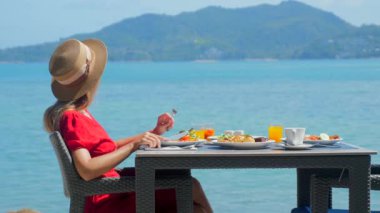 Tatilde olan genç bir kadın lüks bir restoranda sağlıklı yiyeceklerle birlikte sabah yemeğinin tadını çıkarıyor. Tayland tatili.