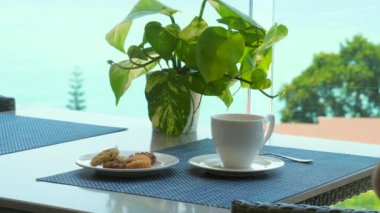 Tropik tatilde, deniz manzaralı kafede sıcak kahve içen bir adam. Deniz manzaralı kafede nefis kahvaltılı cennet. Tayland 'da yaz tatili. Günaydın..