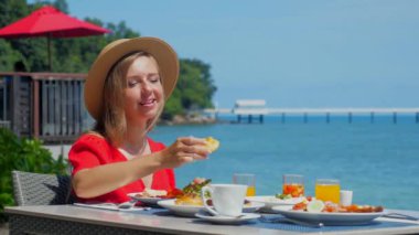 Yaz tatilindeki mutlu bir kadının portresi. Deniz manzaralı açık büfede kahvaltı yapıyor. Seyahat, turizm, Tayland 'da tatil