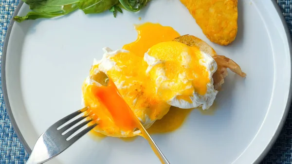 英語の朝食 ポーチドエッグ ベーコン トーストのクローズアップ 女性の手パンの上に目玉焼き黄身とベネディクト卵を切断 健康的な食事 トップ表示 — ストック写真