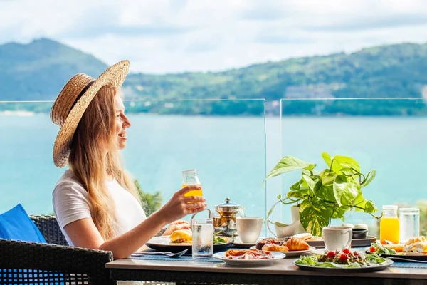 坐在咖啡桌旁笑着的女人欣赏着大海中的橙汁 在热带度假胜地的暑假在旅馆里吃早餐 Phuket Island Thailand Asia — 图库照片