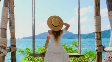 Yaz yolculuğu konsepti. Hasır şapkalı kadın okyanusa tepeden bakan deniz manzaralı mutluluk ve özgürlükle sallanıyor. Mükemmel bir tatil ve tatil kaçışı. Arka plan.