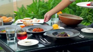 Sahil kenarındaki bir restoranda bir garson konukların özel etkinlikleri kutlayabileceği ya da arka planda çarpıcı bir deniz manzarası olan hafta sonu yemeğinin tadını çıkarabileceği bir masaya katılır. Yavaş çekim