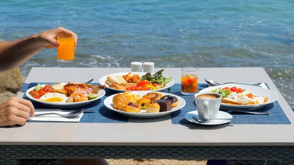 Enjoy a delicious breakfast at a tropical hotel resort. Man drinking orange juice on buffet breakfast at a luxurious beachfront villa. Dining at a beachside restaurant
