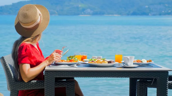 一位正在渡假的年轻女子在一家俯瞰美丽大海的豪华度假胜地餐厅享用早餐 热带天堂的自由与幸福 — 图库照片