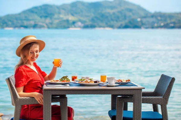 Tatilde olan genç bir kadın lüks bir restoranda sağlıklı yiyeceklerle birlikte sabah yemeğinin tadını çıkarıyor. Tayland tatili.