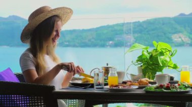 Deniz manzaralı bir kafede dinlenen, salata ve yumurta gibi taze sağlıklı yiyecekler yiyen bir kadın. Yaz tatillerinde Tayland, Asya 'daki tropik Phuket Adası' nda otel kahvaltısının tadını çıkarıyorum..