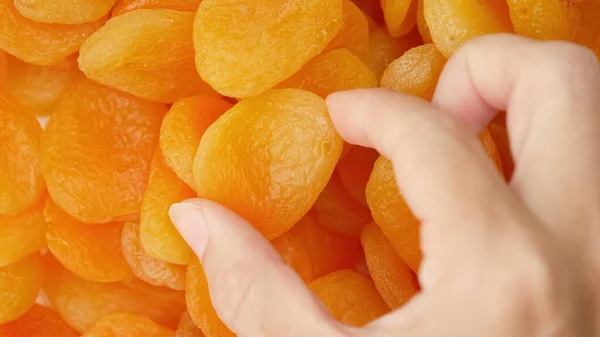 Die Hand Der Frau Nimmt Eine Leuchtend Gelbe Getrocknete Aprikose — Stockfoto