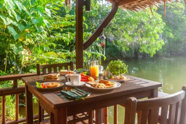 Manzaralı göl manzaralı bir otelde gurme kahvaltı ziyafeti. Lezzetli yemeklerle lezzetlerin tadını çıkar. Tayland tatili kavramı.