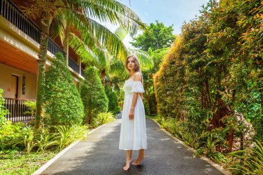 Beyaz elbiseli kadın Bali 'deki yemyeşil tropikal arazide geziniyor, doğanın güzelliğini kucaklıyor. Seyahat ve yaz tatili kavramı.