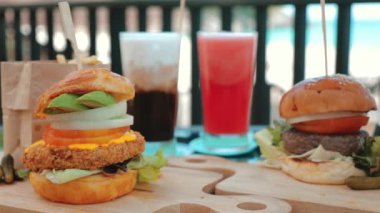 Peynirli iki büyük burger, marul ve taze buzlu karpuz suyu ve latte ile birlikte ızgara biftek. Lezzetli sahil tatili yemeklerine düşkünlük kavramı.