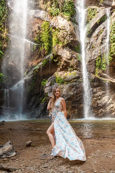 Serene waterfall, lady in elegant dress. Embrace natures allure, tranquil river in the forest. Escape to tropical bliss.