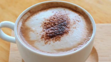 Tahta masada sıcak kapuçino, kremalı köpük, zengin aroma, espresso, süt girdabı, sabah kahvesi. Sıcak bir kafede buharlı kapuçino.